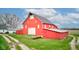 Exterior view of a red barn with white trim, set amidst green fields and mature trees under a bright sky at 10573 W 550 N, Thorntown, IN 46071