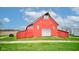 Exterior shot of a well-maintained red barn with a gravel driveway and green surroundings in a rural setting at 10573 W 550 N, Thorntown, IN 46071