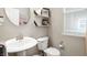 A half bathroom features white fixtures, a pedestal sink, a round mirror, and a toilet with storage shelves at 15046 Sullivan Ln, Westfield, IN 46074