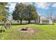 Beautiful backyard featuring mature trees, a brick firepit, and a swing set at 1617 S N St, Elwood, IN 46036