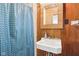 Bathroom featuring wood walls, sink with mirror, and a shower with blue curtain at 1617 S N St, Elwood, IN 46036