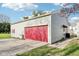 Detached garage with siding, red garage door, and concrete driveway on a sunny day at 1617 S N St, Elwood, IN 46036