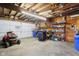 Well lit garage with visible overhead beams and shelves. Lawn mower and snow blower visible at 1617 S N St, Elwood, IN 46036