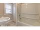 Bathroom with a toilet, sink, and a bathtub with white enclosure and a window with natural light at 2620 Central Ave, Indianapolis, IN 46205