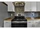 Close-up of a sleek, stainless steel range and hood, complemented by white cabinetry and stunning backsplash at 3701 Dorval Pl, Indianapolis, IN 46228