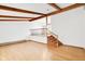 Bright living room featuring hardwood floors, exposed wood beams, and a staircase at 4935 W Carriage Dr, New Palestine, IN 46163