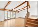 Sun-lit living room with exposed beams, hardwood floors, and large windows at 4935 W Carriage Dr, New Palestine, IN 46163