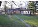 Spacious backyard featuring a sunroom, a small deck, a brick walkway, and mature trees at 5819 Bar Del E Dr, Indianapolis, IN 46221
