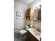 Charming bathroom featuring decorative wallpaper, wood cabinets, white tile, and a framed art piece at 5819 Bar Del E Dr, Indianapolis, IN 46221