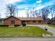 Charming brick home featuring a ramp, attached garage, and well-manicured lawn at 619 Heritage Ln, Anderson, IN 46013