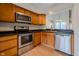 Functional kitchen with stainless steel appliances, wood cabinets, and a pass-through to the dining area at 7352 Crickwood Pl, Indianapolis, IN 46268