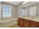Well-lit bathroom featuring a double vanity, soaking tub, and a large window at 8613 N Meridian St, Indianapolis, IN 46260