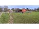 Exterior view of a red barn with fenced paddocks and a pony grazing nearby on a sunny day at 11686 S 825 W, Edinburgh, IN 46124