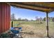 View of a grassy paddock with fencing, distant barn, and a blue wheelbarrow filled with hay at 11686 S 825 W, Edinburgh, IN 46124