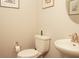 Powder room with classic toilet, framed art, and decorative round mirror over the pedestal sink at 1274 Clairet, Westfield, IN 46074