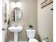 A clean powder room with a pedestal sink, toilet, and decorative mirror and wall hangings at 1684 Beach St, Greenwood, IN 46143