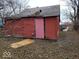 Rear exterior of a red house needing repair, with damage to the roof and siding at 1724 Sheldon St, Indianapolis, IN 46218