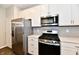 Bright kitchen features stainless steel appliances, stylish cabinets, quartz countertop and dark wood flooring at 1803 Jackson St, Fortville, IN 46040