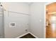 Bright laundry room with grey walls, black wood-look floors, utility connections, and a wire shelf for organized storage at 1803 Jackson St, Fortville, IN 46040