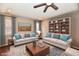 Staged living room featuring neutral couches, built-in shelving, a ceiling fan, and a decorative rug at 1803 Jackson St, Fortville, IN 46040