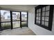 Outdoor porch area with wooden floors, a screen door, and white siding with a black framed window at 2028 George St, Anderson, IN 46016