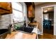 Kitchen featuring a black sink, wood countertop, gray backsplash, and a view of the dining room with blue chairs at 4910 East 21St St, Indianapolis, IN 46218