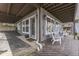Exterior view featuring a covered patio with white chairs, wooden floors, and a glimpse of the surrounding landscape at 6290 Grouse Dr, Nineveh, IN 46164