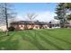 A sprawling backyard featuring a pristine lawn and a sunroom extension of the home, perfect for outdoor enjoyment at 6407 Brokenhurst Rd, Indianapolis, IN 46220