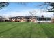 Expansive backyard with a lush green lawn and a charming sunroom addition to the home at 6407 Brokenhurst Rd, Indianapolis, IN 46220