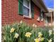 Close up of brick siding and green shutters with spring flowers in bloom at 810 Fabyan Rd, Indianapolis, IN 46217