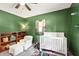 Bright bedroom with carpet, green walls, ceiling fan, and a crib at 859 E Bunkerhill Rd, Mooresville, IN 46158