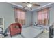 Bright bedroom with red chair, ceiling fan, and plenty of natural light from the windows at 1231 S Pershing Ave, Indianapolis, IN 46221
