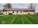 A single-story home boasts an expansive, well-manicured backyard with lush green grass and mature trees at 18103 N 300 W, Summitville, IN 46070