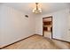 A carpeted room with neutral walls and a chandelier light fixture features a view into the adjacent kitchen at 3451 N County Road 100 E, Danville, IN 46122