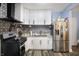 White cabinet kitchen with a stainless steel fridge and a black and white tiled backsplash at 3940 N Drexel Ave, Indianapolis, IN 46226