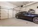 Modern garage with a dark blue sedan, epoxy floors, automatic door, and built-in storage for organization at 4030 Statesmen Dr, Indianapolis, IN 46250