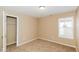 A bedroom with neutral paint, carpet, and window next to an open closet at 5010 Elliott Ave, Indianapolis, IN 46201