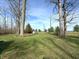 Spacious backyard featuring lush green grass, mature trees, and a storage shed in the distance at 5967 Oak Hill East Dr, Plainfield, IN 46168