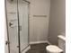This bathroom includes a walk-in shower with glass doors, new toilet and gray walls at 6044 Granner Dr, Indianapolis, IN 46221