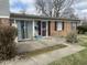 Charming brick and vinyl exterior with a concrete patio, features a security door and mature shrubbery at 6808 Summer Time Dr, Indianapolis, IN 46226