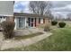 Charming brick and vinyl exterior with a concrete patio, features a security door and mature shrubbery at 6808 Summer Time Dr, Indianapolis, IN 46226
