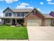 Two-story home featuring a well-manicured lawn, brick accents, and a spacious three-car garage at 7233 Capel Dr, Indianapolis, IN 46259