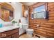 Log-walled bathroom with wood vanity, toilet, and mirror reflecting cabinet at 98 Highland Manor S Ct, Indianapolis, IN 46228