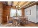 Log dining room with wood table and chairs illuminated by chandelier and natural light at 98 Highland Manor S Ct, Indianapolis, IN 46228
