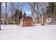 A charming shed sits on a snow-covered lot with bare trees and an outbuilding in the background at 98 Highland Manor S Ct, Indianapolis, IN 46228