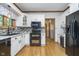 Updated kitchen with white cabinetry, a black appliance suite, mosaic backsplash, hardwood floors, and lots of natural light at 1143 N Sugar Bend Run, Greenfield, IN 46140