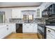 Cozy kitchen with white cabinets, mosaic backsplash, hardwood floors, and a black appliance suite at 1143 N Sugar Bend Run, Greenfield, IN 46140