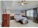 Bedroom with tray ceiling, ceiling fan, and bedside tables with lamps next to a large window at 1401 Shadow Ct, Zionsville, IN 46077