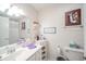A well-lit bathroom features a mirror, white cabinets, decorative wallpaper, and a toilet for a functional space at 142 Norbeck Ter, Indianapolis, IN 46217