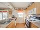 Well-lit kitchen with light wood cabinets, a full suite of appliances, and laminate flooring at 142 Norbeck Ter, Indianapolis, IN 46217